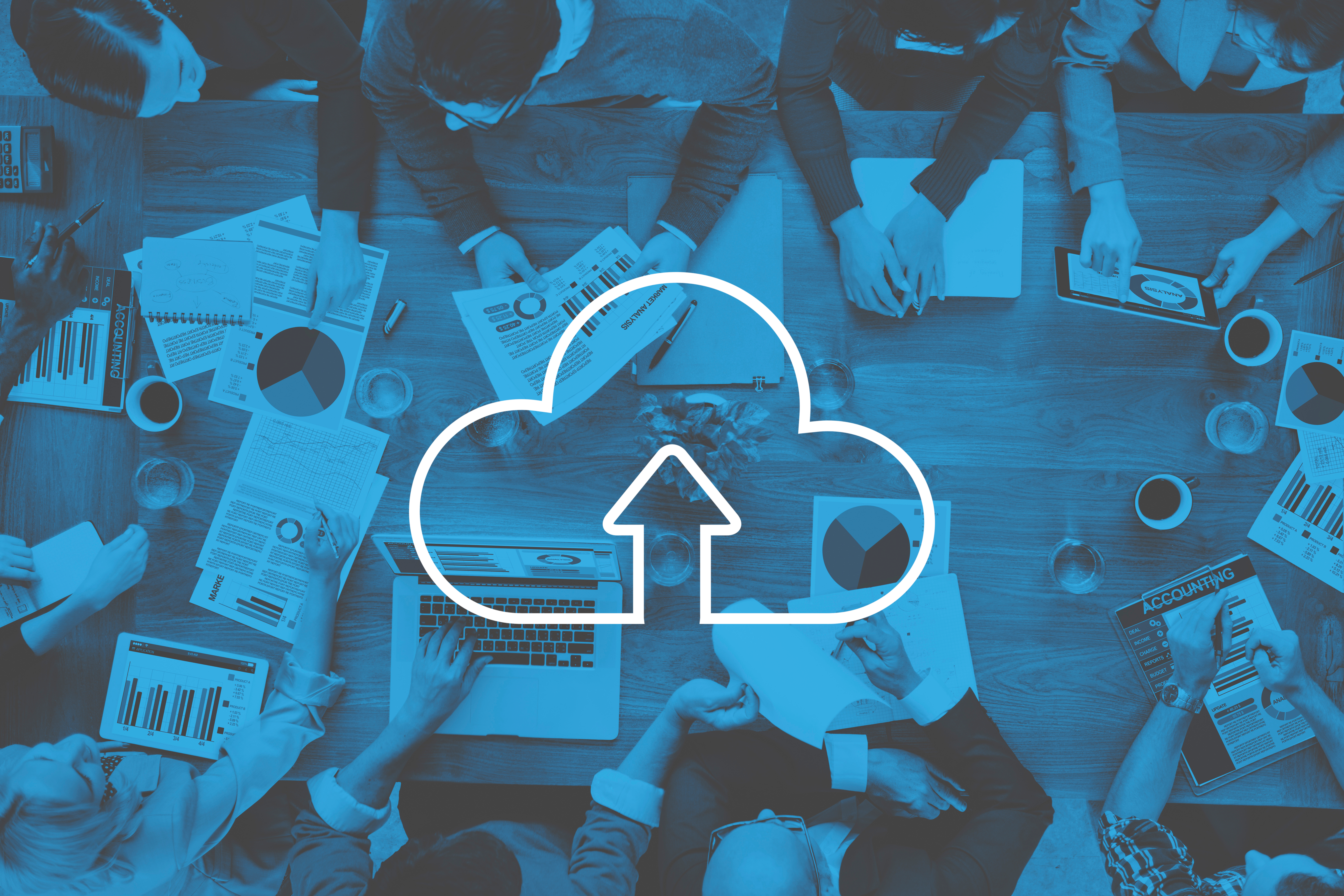 Team collaborating around a table with a cloud upload icon overlay